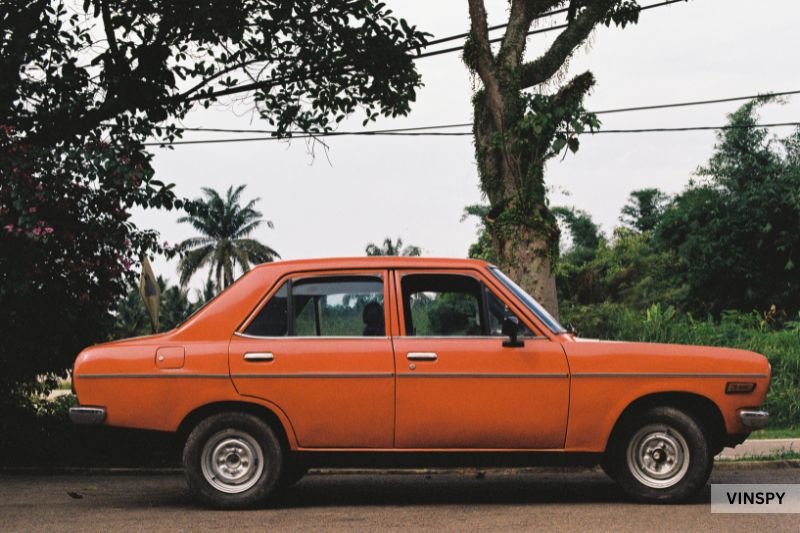 Old orange car parked roadside symbolising how much an accident devalues a car over time.
